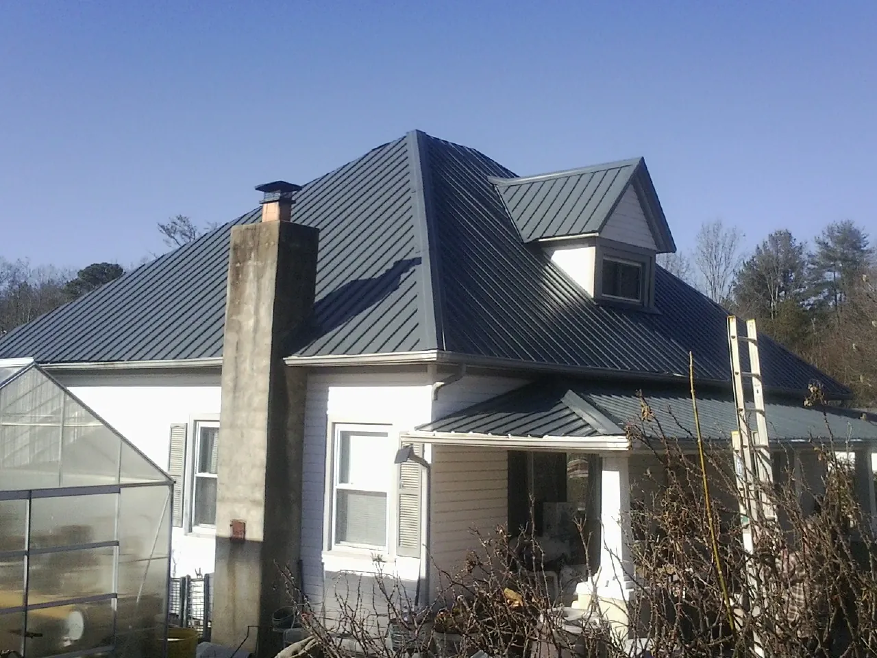 Dark blue standing seam metal roof on a white farmhouse with dormer — Slate & Tile Roof Repair by Roofing Brothers in Branchport
