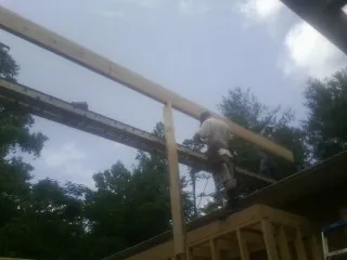 Carpenter setting a ridge beam over a new addition frame — Ice Dam Removal by Roofing Brothers in Branchport