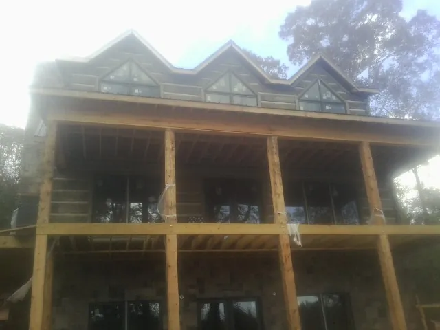 Dormers and porch framing on a large log home under construction — Roof Coating work by our crew in Branchport