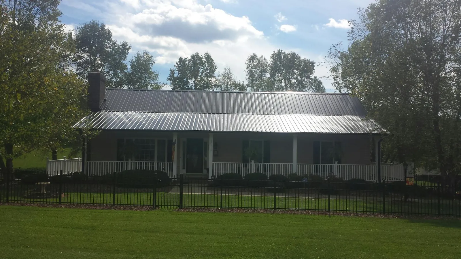 Gray metal roof on a brick ranch with a full width front porch — Gutter Guard Installation work by our crew in Branchport