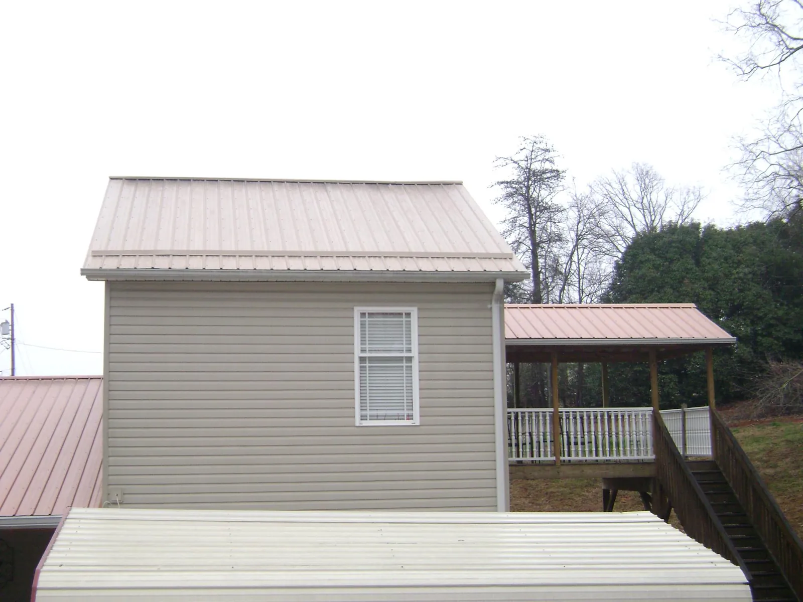 Tan metal roofs on a two story addition and attached porch, from a Roof Replacement job in Branchport