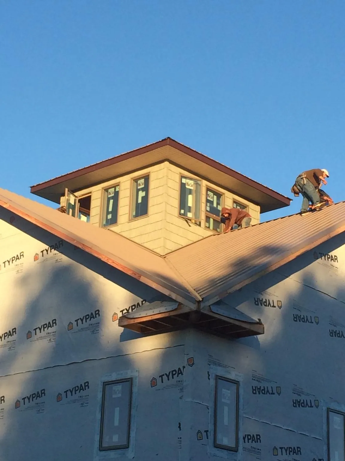 Roofers working around a rooftop cupola on a new metal roof at sunset — Roof Waterproofing in Branchport by Roofing Brothers